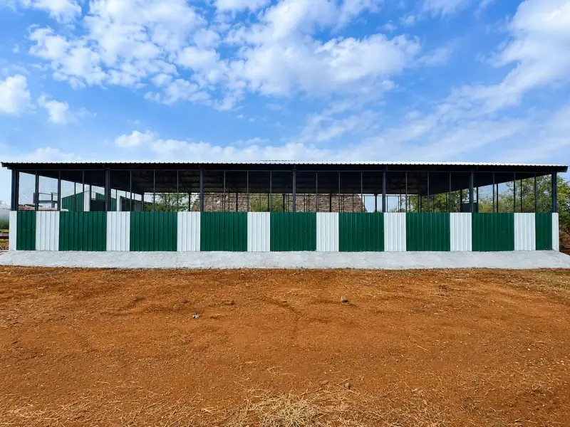 Front view of a green-and-white animal shed with mesh side walls