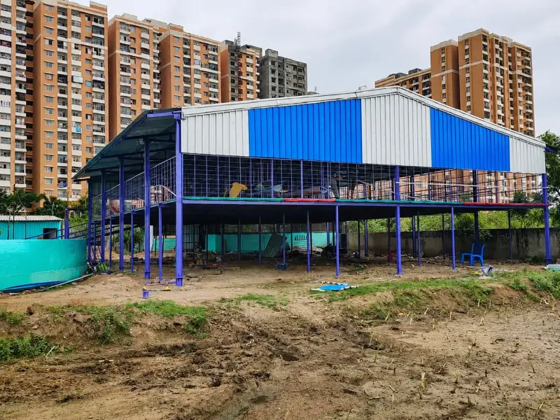 Elevated goat shed under construction next to high-rise apartments