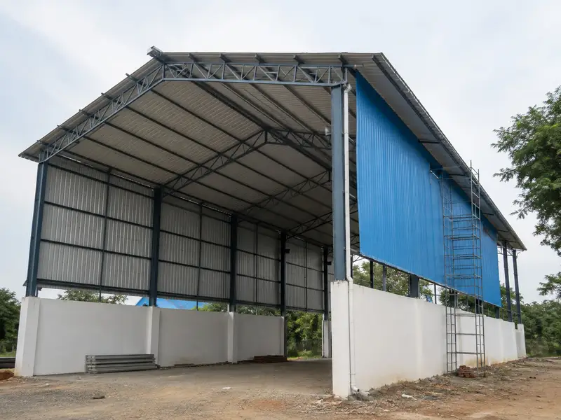 Factory shed under construction with white plinth walls and blue sheeting